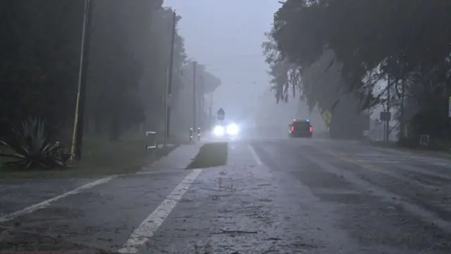 A police car (R) drives through heavy rains in Archer, Florida, on August 30, 2023, after Hurricane Idalia made landfall. Idalia barreled into the northwest Florida coast as a powerful Category 3 hurricane on Wednesday morning, the US National Hurricane Center said.