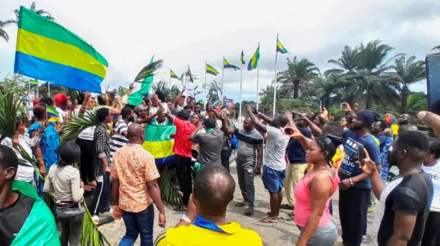 People in Librevillem Gabon wave the national flag as the celebrate the military takeover