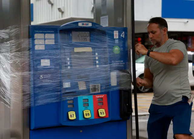 Nazih Tageddine wraps cellophane around his gas pump to prevent it from being damaged by the rain from Hurricane Idalia as it passes offshore on August 29, 2023 in Clearwater Beach, Florida. Hurricane Idalia is forecast to make landfall on the Gulf Coast of Florida Wednesday morning.