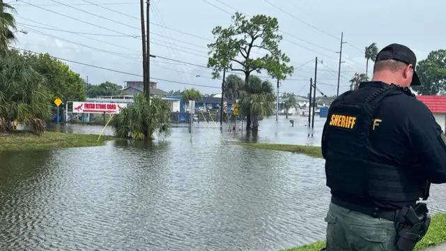 A sheriff stands in a flooded area near Highway 19