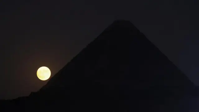 A full moon known as the "Blue Moon" rises behind the Pyramids of Giza in Egypt, August 30