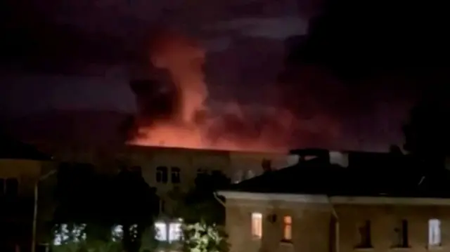 A plume of smoke is illuminated by a flash of light amid a drone attack in Pskov, Russia, in this still image obtained from social media video released on Wednesday