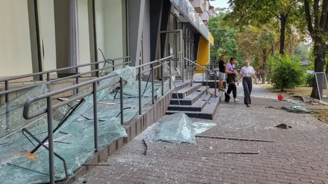 Staff clean up broken windows of a store damaged during a Russian missile strike, amid Russia's attack on Ukraine