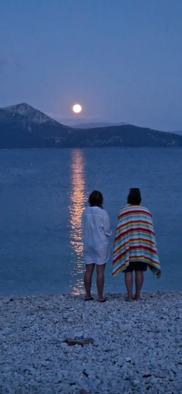 Two women wrapped in towels looking at the Moon