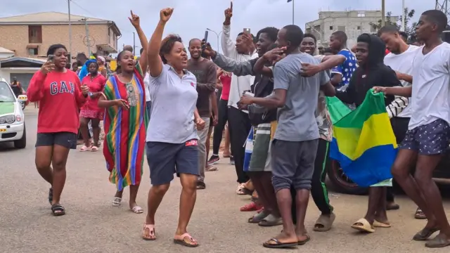 A crowd of people celebrate on the streets of Port Gentil, some of the waving Gabonese flags