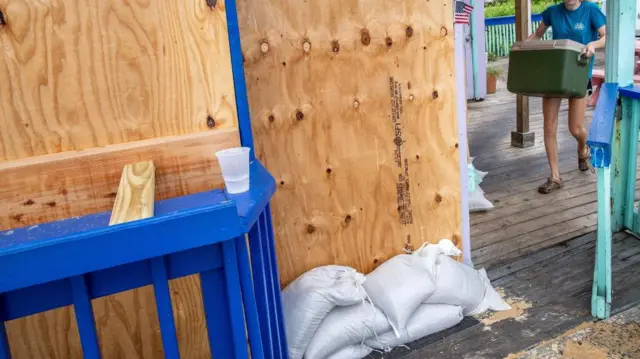 A woman walks with her belongings next to a building covered with plywood as the town prepares for Hurricane Idalia in Cedar Key, Florida, USA, 29 August 2023