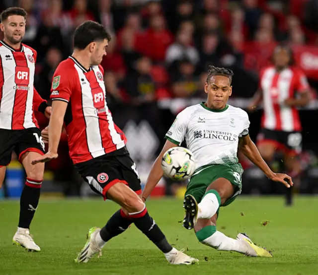 Alistair Smith of Lincoln City takes a shot on goal ahead of John Egan