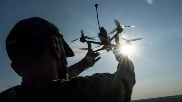 A Ukrainian soldier holds a drone aloft