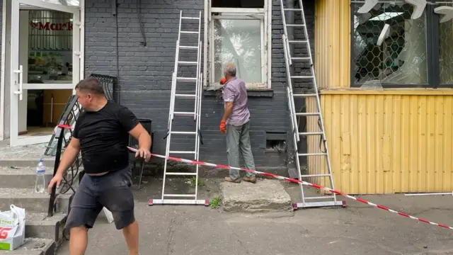 Men clear up debris outside a shop