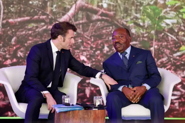 Gabon's President Ali Bongo (R) speaks to French President Emmanuel Macron (L) during the One Forest Summit at the Presidential Palace in Libreville on March 2, 2023.