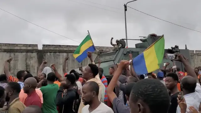 A still from a social media video shows people in Port-Gentil, Gabon, celebrating as a military vehicle passes them