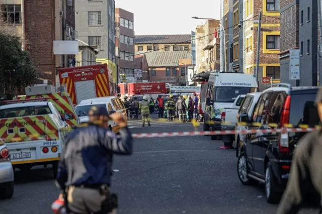 South African firefighters and South African Police Service officers work at the sceen of a fire in Johannesburg