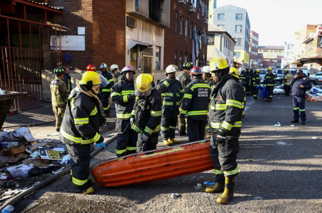 A group of firefighters stand together near the scene of the fire