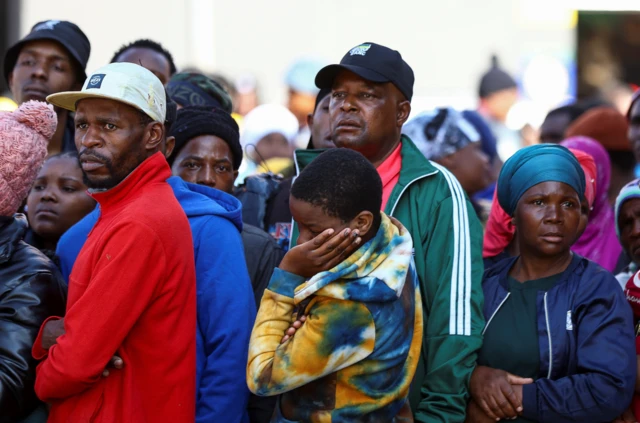 A woman leans her head on her hand as other people look on