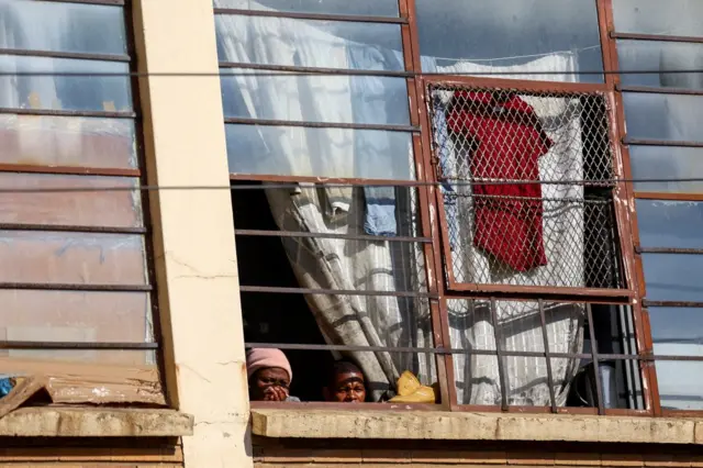 Residents watch from a window the scene of a deadly blaze in Johannesburg