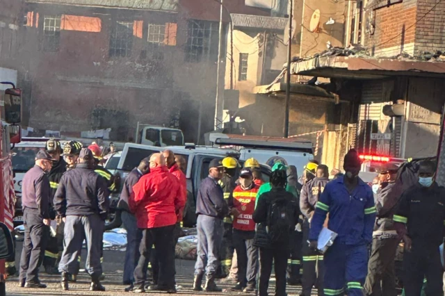 Firefighters, emergency workers and forensic experts at the fire site in Johannesburg