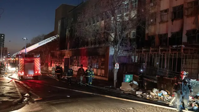 Fire fighters work at the scene of a deadly blaze in the early hours of the morning, in Johannesburg, South Africa