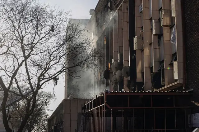 A building in Johannesburg smoulders after fire crews tackle a blaze which has so far killed 52 people