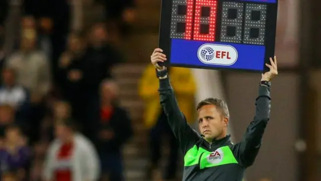 Fourth official holds up board