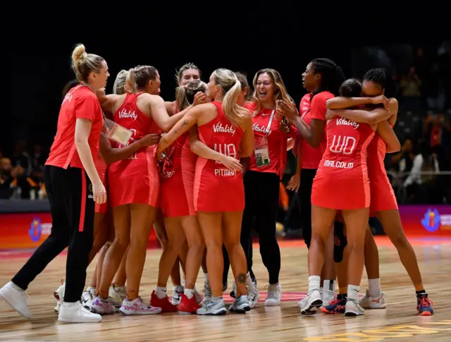 England players huddle together in celebration.