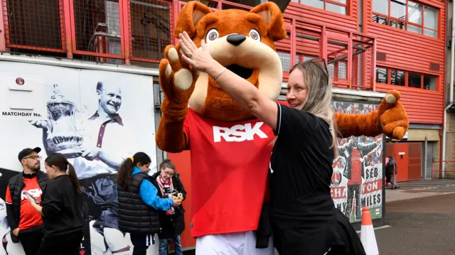 Charlton's mascot dances with a fan