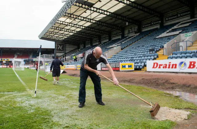 A Dundee groundsman clears the pitch of water