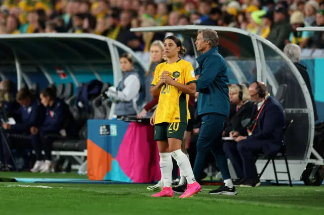 Sam Kerr waits on the sideline to come on to the pitch.