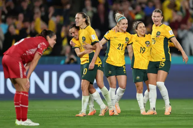 Australia celebrate in front of a deflated denmark defender.