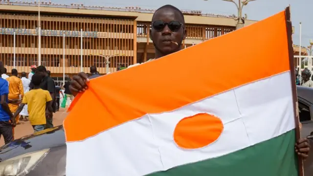 A man displays a Niger flag on his way to a rally in a stadium in Niamey, Niger, 06 August 2023