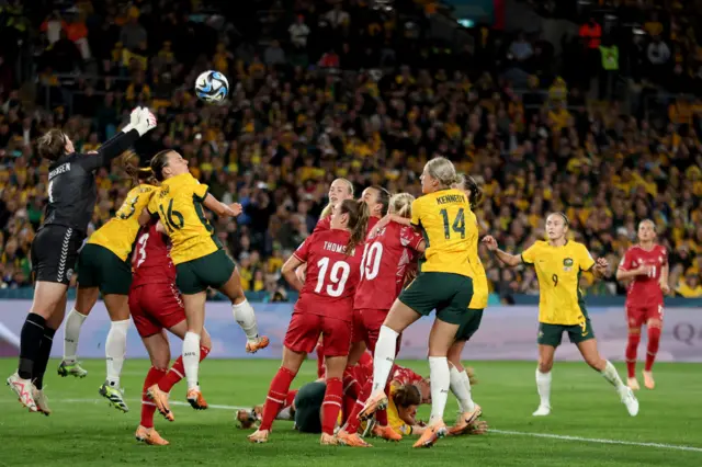 Christensen punches a corner ball away above a crowd of players in the box.