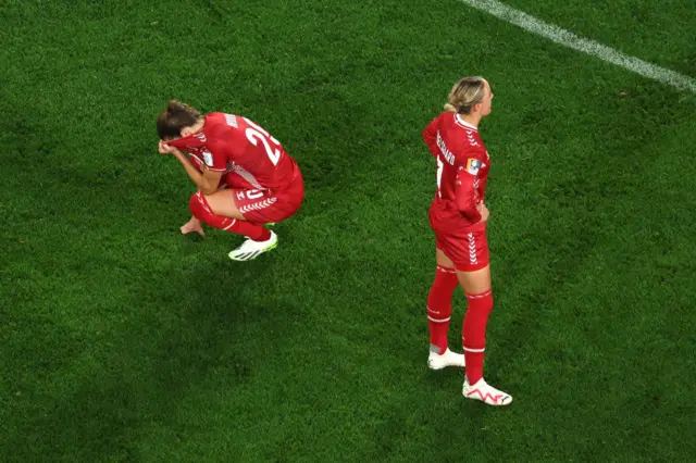 Denmark players stand desconsolate on the pitch.