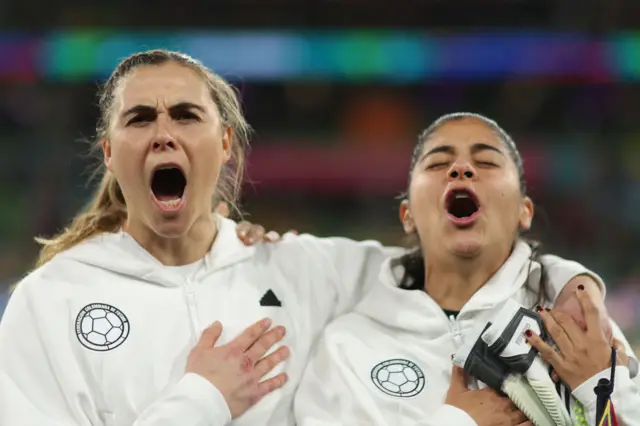 Colombia players shout the national anthem passionately.