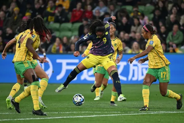 Jamaica players surround a colombia attacker in the box.
