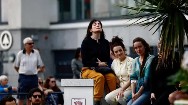 A woman sits with her eyes closed