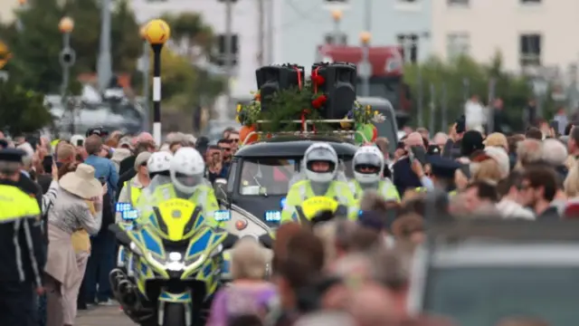 a police escort guides a car through a street