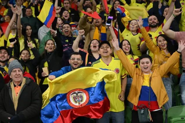 Colombia fans cheer and wave flags in the stands.