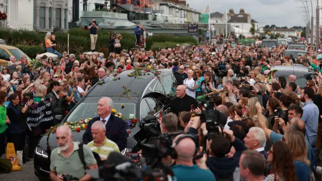 O'Connor's hearse, adorned with flowers, pauses outside her former home in Bray