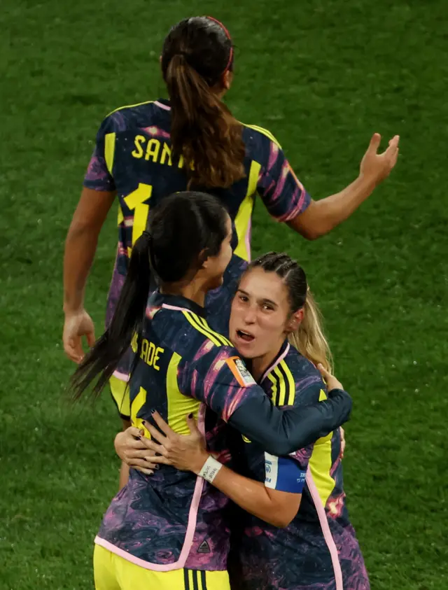 Colombia players celebrate together with hugs at full time.