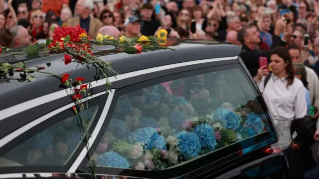 Flowers are piled in a car window