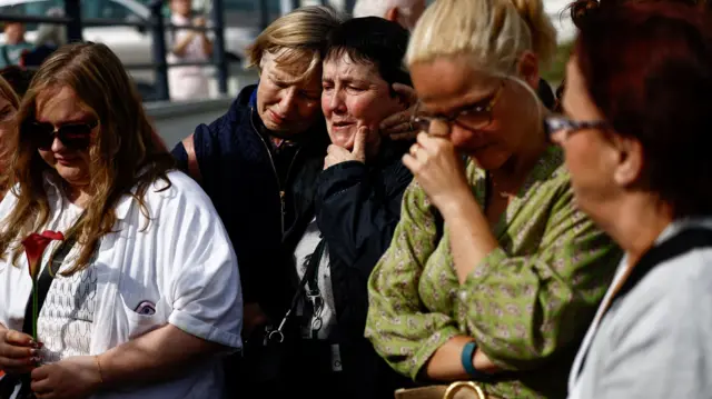 People react as fans gather outside late Irish singer Sinead O'Connor's former home to say their last goodbye to her on the day of her funeral procession, in Bray, Ireland, August 8, 2023.