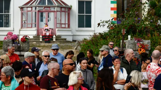 Fans gather outside late Irish singer Sinead O'Connor's former home to say their last goodbye to her on the day of her funeral procession, in Bray, Ireland, August 8, 2023.