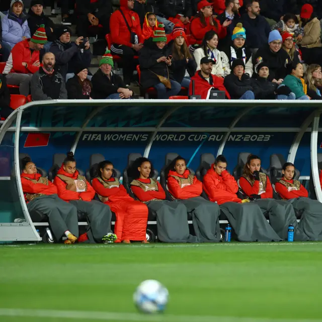 Morocco players sit wrapped up on the bench.