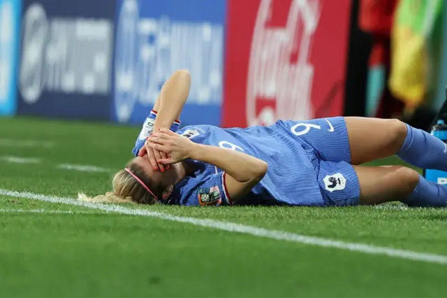 Le Sommer lays stricken with her hands to her head after a late challenge.