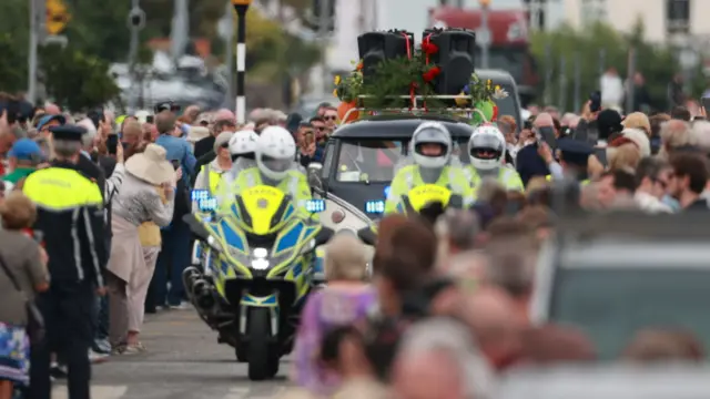 Police lead the hearse to a private burial