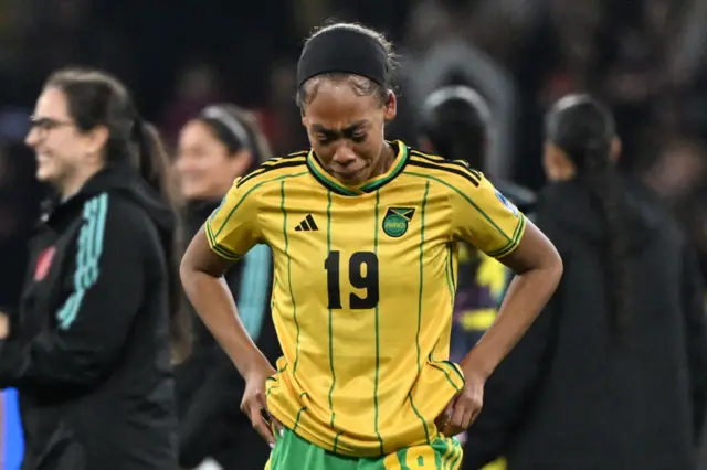 A Jamaica player stands with hands on hips in tears at full time.