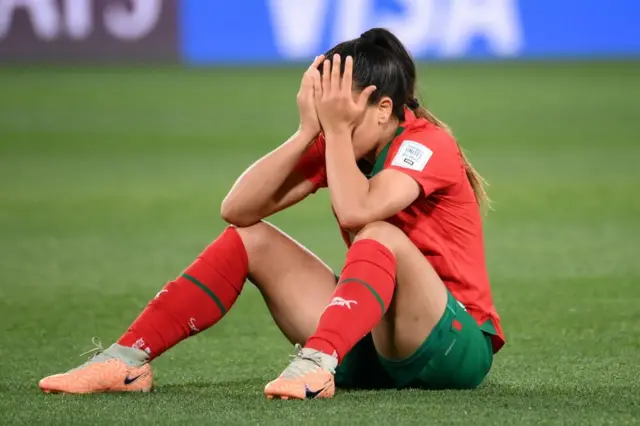 A player holds her head in her hands after Morocco are defeated by France.