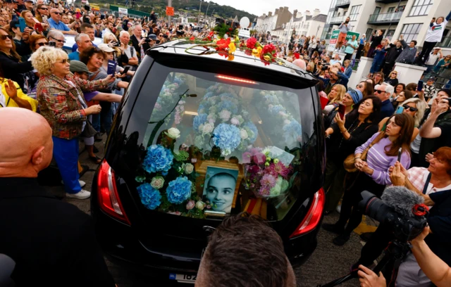 The coffin itself was covered in blue and pink flowers.