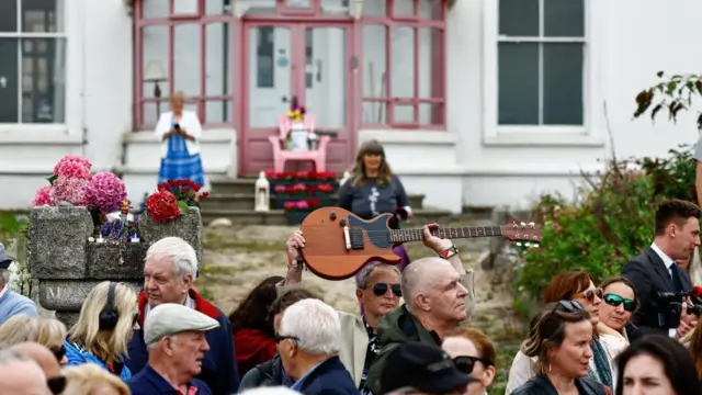 A man holds a guitar aloft in a crowd