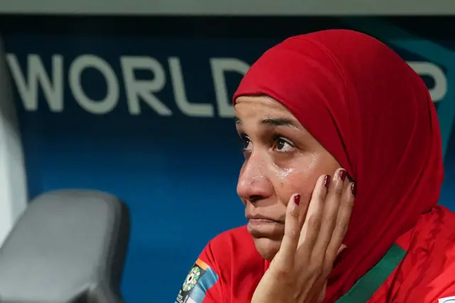 Benzina's face is soaked with tears as she sits on the bench at full time.