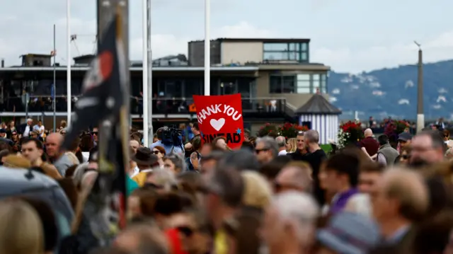 People gather outside late Irish singer Sinead O'Connor's former home to say their last goodbye to her on the day of her funeral procession, in Bray, Ireland, August 8, 2023.